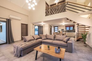A modern living room with a sectional sofa, a wooden coffee table, and a staircase leading to an upper level.