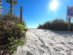 Uma praia arenosa com uma barreira de corda e um aviso indicando o encerramento da praia às 22h.