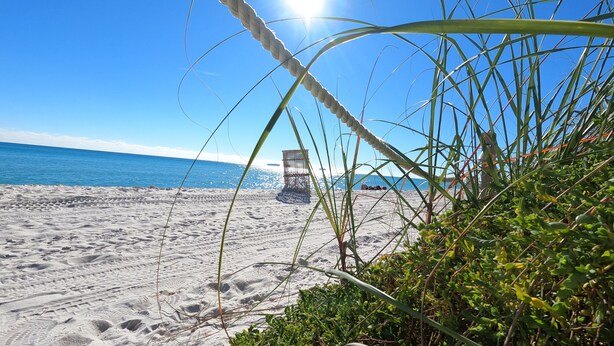 A beach with a clear sky, a rope, and a structure in the distance.