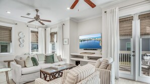 A spacious living room with a white sofa, striped armchair, and a flat-screen TV mounted on the wall. - 3BR Prominence 30A Townhome Near Pool, Sleeps 10 - Spring openings (Watersound)