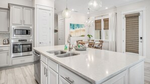 A modern kitchen with white cabinetry, stainless steel appliances, a large island with a sink, and pendant lighting. - 3BR Prominence 30A Townhome Near Pool, Sleeps 10 - Spring openings (Watersound)