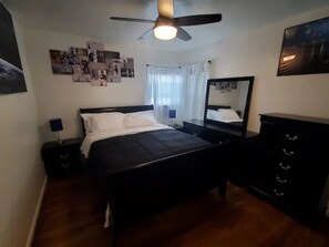 Relax in this serene bedroom with a large bed, two nightstands, and a ceiling fan above.