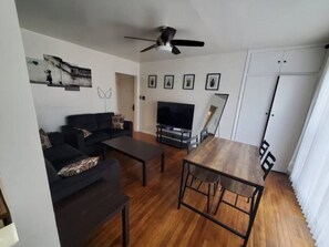 Relax in this stylish living room with a flat-screen TV, dining table, and comfortable sofa.