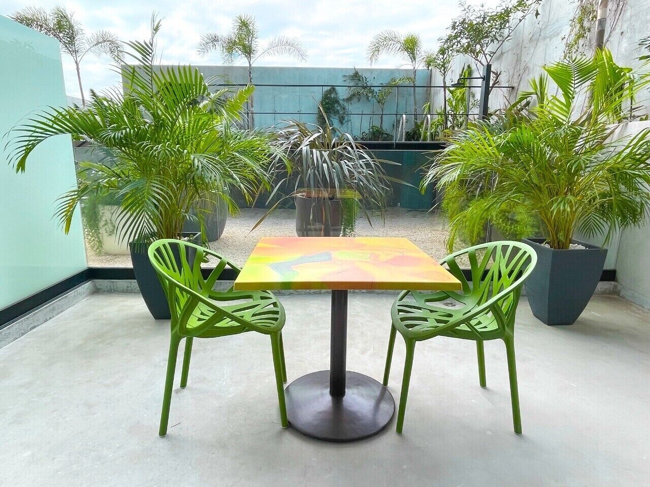 Een terras met een tafel en stoelen, omringd door plantenpotten.