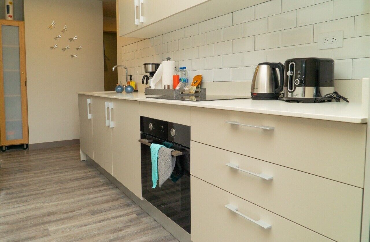 Een moderne keuken met een ingebouwde oven, een koffiezetapparaat en een waterkoker op het aanrecht.