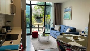 A modern living room with a blue sofa, a coffee table, and a kitchen area with a blender and a kettle. - Cozy apartment with terrace Cosmopolitan Tower, Nunciatura, San Jose (San José)