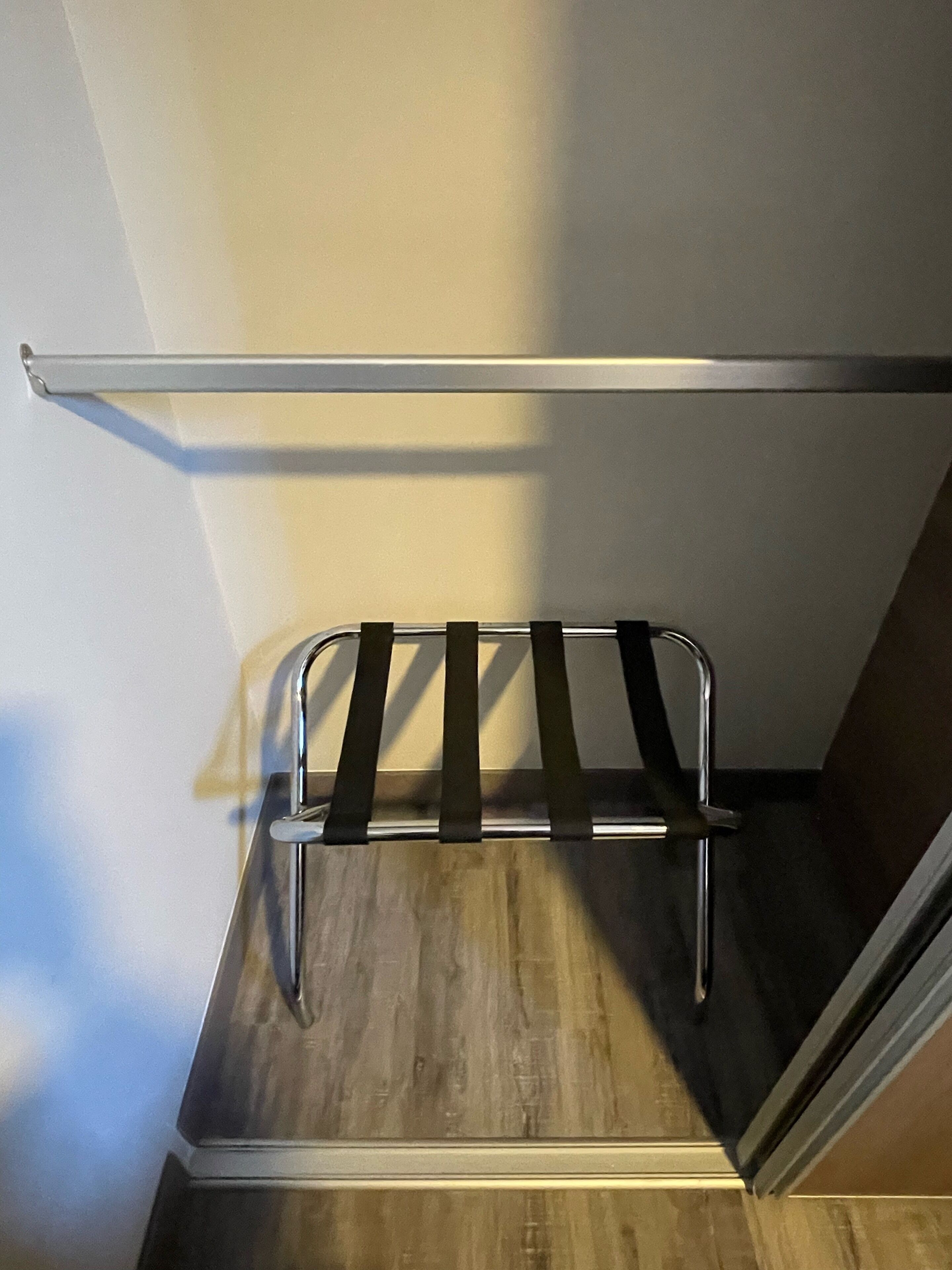 Un coin de pièce avec un plancher en bois, un étagère en métal et un mur blanc.