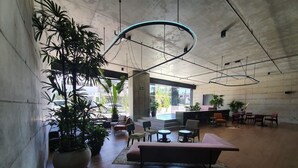 A spacious lobby with a modern design, featuring a large potted plant, seating areas, and a unique ceiling light fixture. - Cozy apartment with terrace Cosmopolitan Tower, Nunciatura, San Jose (San José)