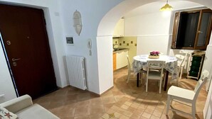 Un accogliente soggiorno con divano, tavolo da pranzo con sedie e cucina sullo sfondo.