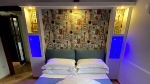 Una camera da letto con un letto, una testiera decorata e due comodini fissati alla parete.