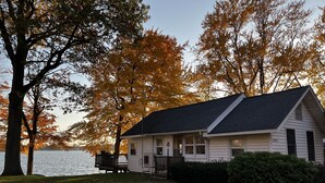 Una casa blanca con techo oscuro, un porche y vistas a un lago.