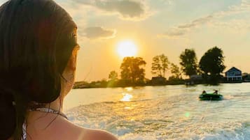 A sunset over a body of water with a house and trees in the background.