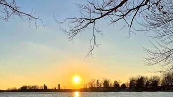 A sunset over a body of water with a park bench in the foreground.