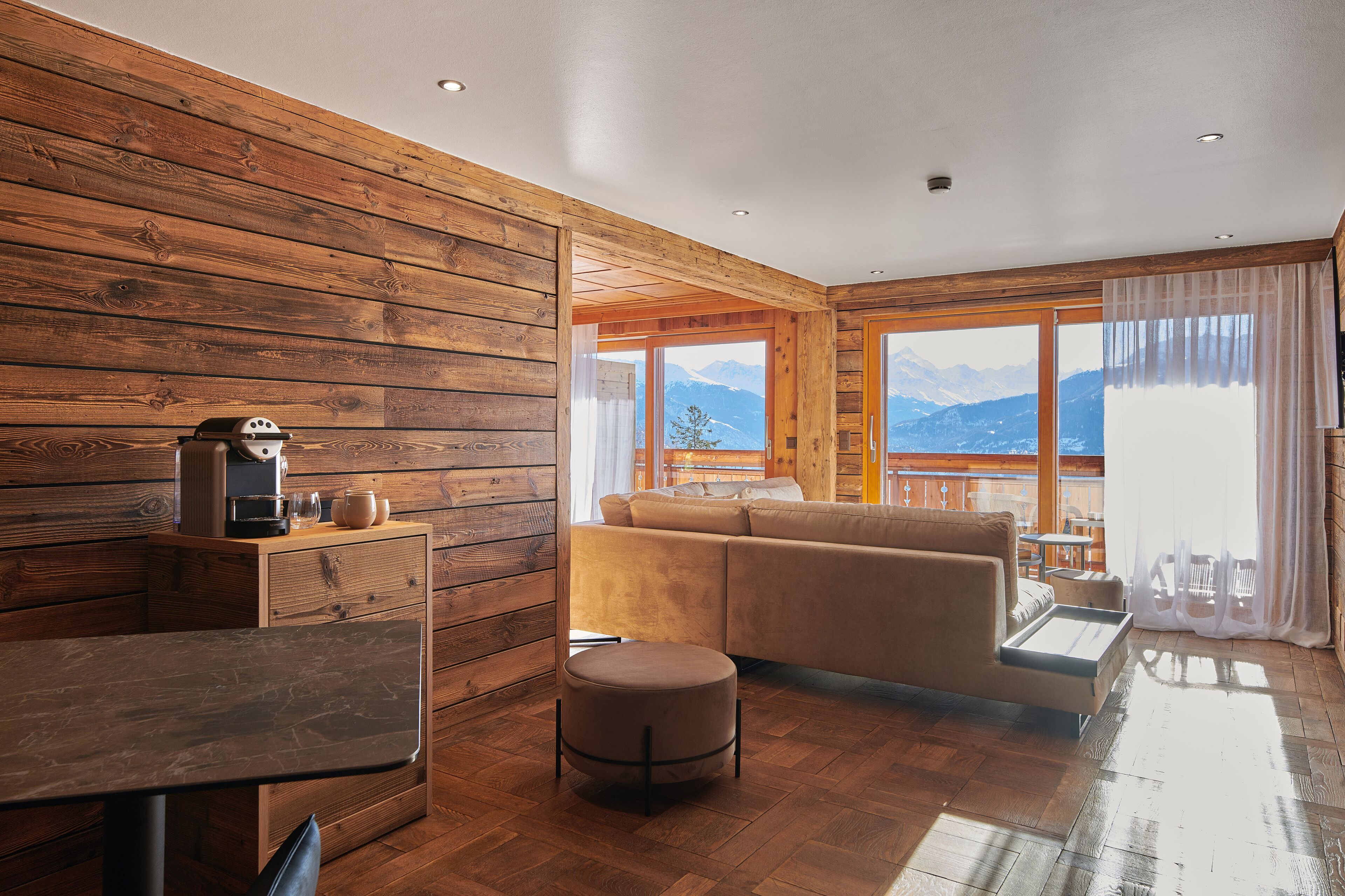 Una habitación acogedora con paredes de madera, un sofá, una mesa y vistas a la montaña.