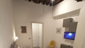 Ein Schlafzimmer mit einem großen Bett, einem Sessel, einem Fernseher und einer Tür.