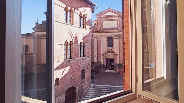 Ein Fenster mit Blick auf ein Gebäude mit Innenhof und Kirche.