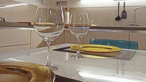 Eine moderne Küche mit einem Glastisch, gedeckt für zwei Personen, mit klarem Glas und einer gewebten Tischmatte.