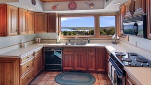 Une cuisine avec des meubles de rangement en bois, une grande fenêtre et une vue sur l’extérieur.