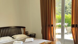 Habitación de hotel con cama, escritorio de madera, mesita de noche y vista a través de un ventanal.