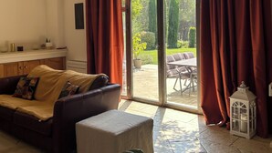 Un salón con sofá, una mesita y vistas a un patio exterior a través de un ventanal.