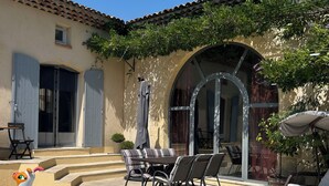 Un área de piscina con una silla de descanso y una mesa, una piscina inflable pequeña y una zona de estar cubierta.