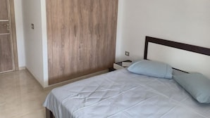 Un dormitorio con cama, armario de madera y mesita de noche.