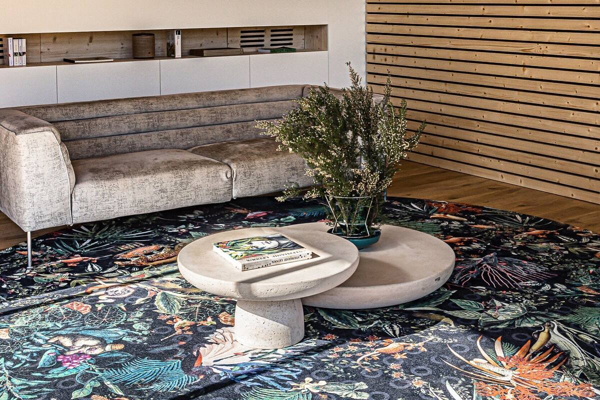 A modern interior with a wooden slatted ceiling, a sofa, a coffee table, and a decorative plant.