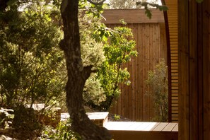Terraza de madera con valla de madera, rodeada de árboles y arbustos.