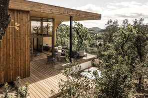 A modern wooden deck with outdoor furniture, a hot tub, and a view of the surrounding landscape. - Souki Lodges & Spa (Cabrières)