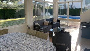 A sunroom with large windows, a ceiling fan, and a pool visible through the glass doors.