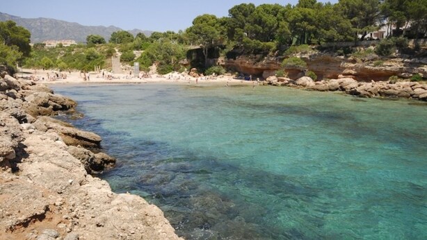 A clear coastal area with rocky shores and a sandy beach.