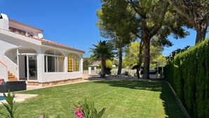 A white building with a covered patio and a well-maintained lawn.