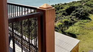 Un balcon donnant sur une mer calme et un paysage vallonné.