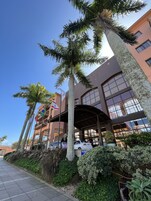 L'ingresso di un hotel con una tettoia, palme e un cielo azzurro intenso.