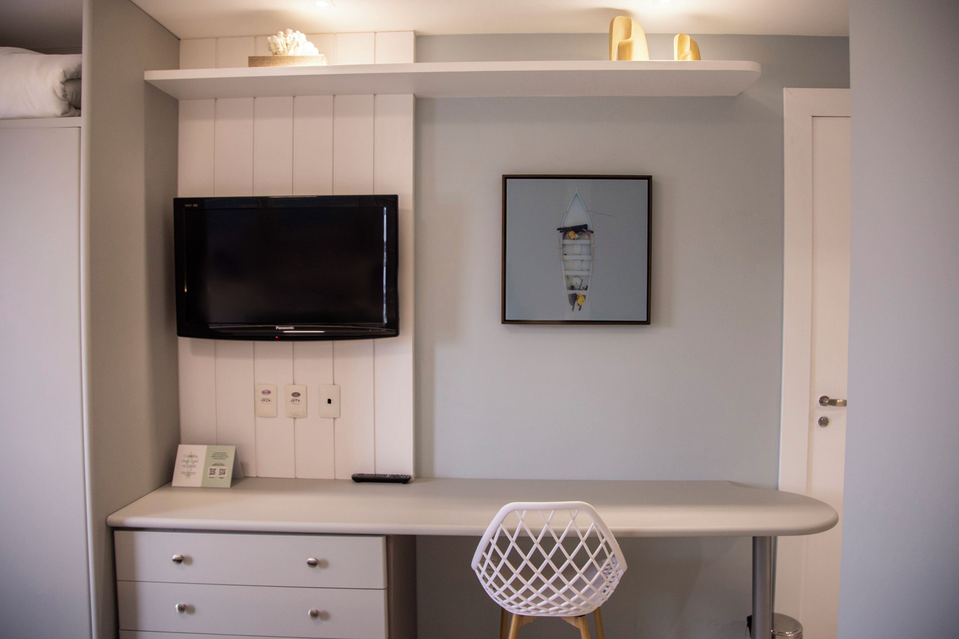 A modern kitchen with a built-in TV, a framed artwork, and a white chair.