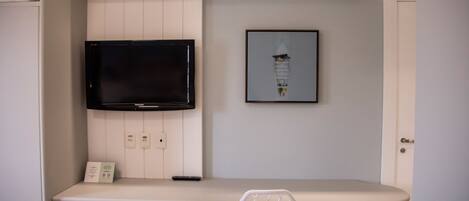 A modern kitchen with a built-in TV, a framed artwork, and a white chair.
