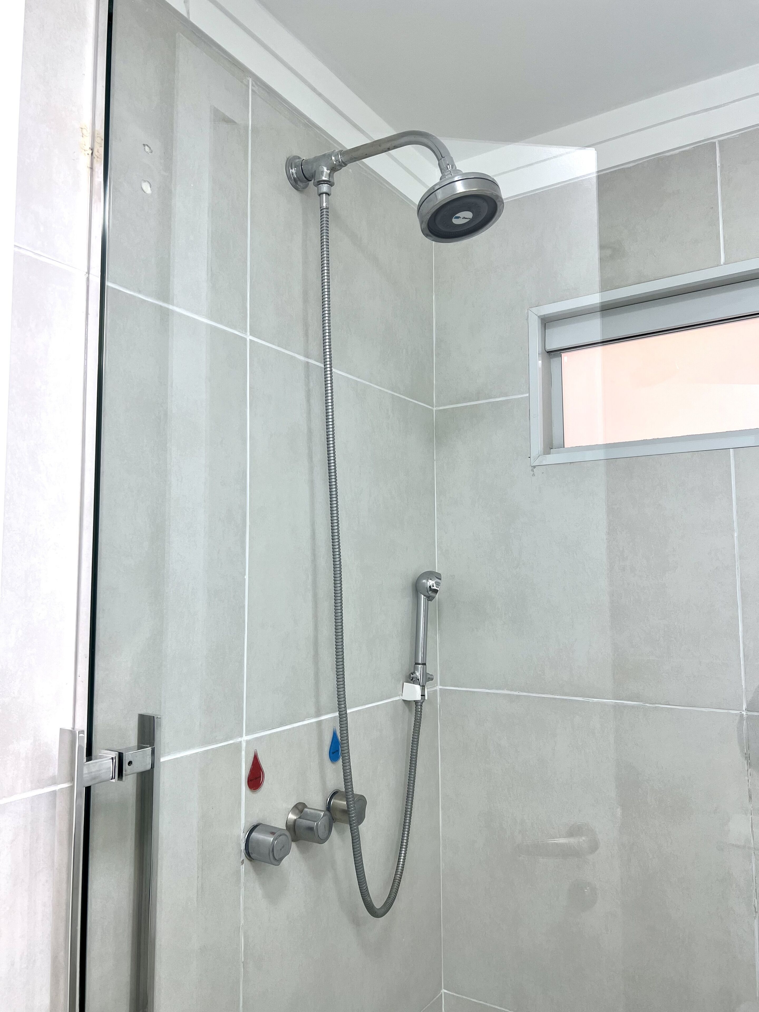 A shower with a handheld showerhead and a fixed showerhead, both mounted on a tiled wall.
