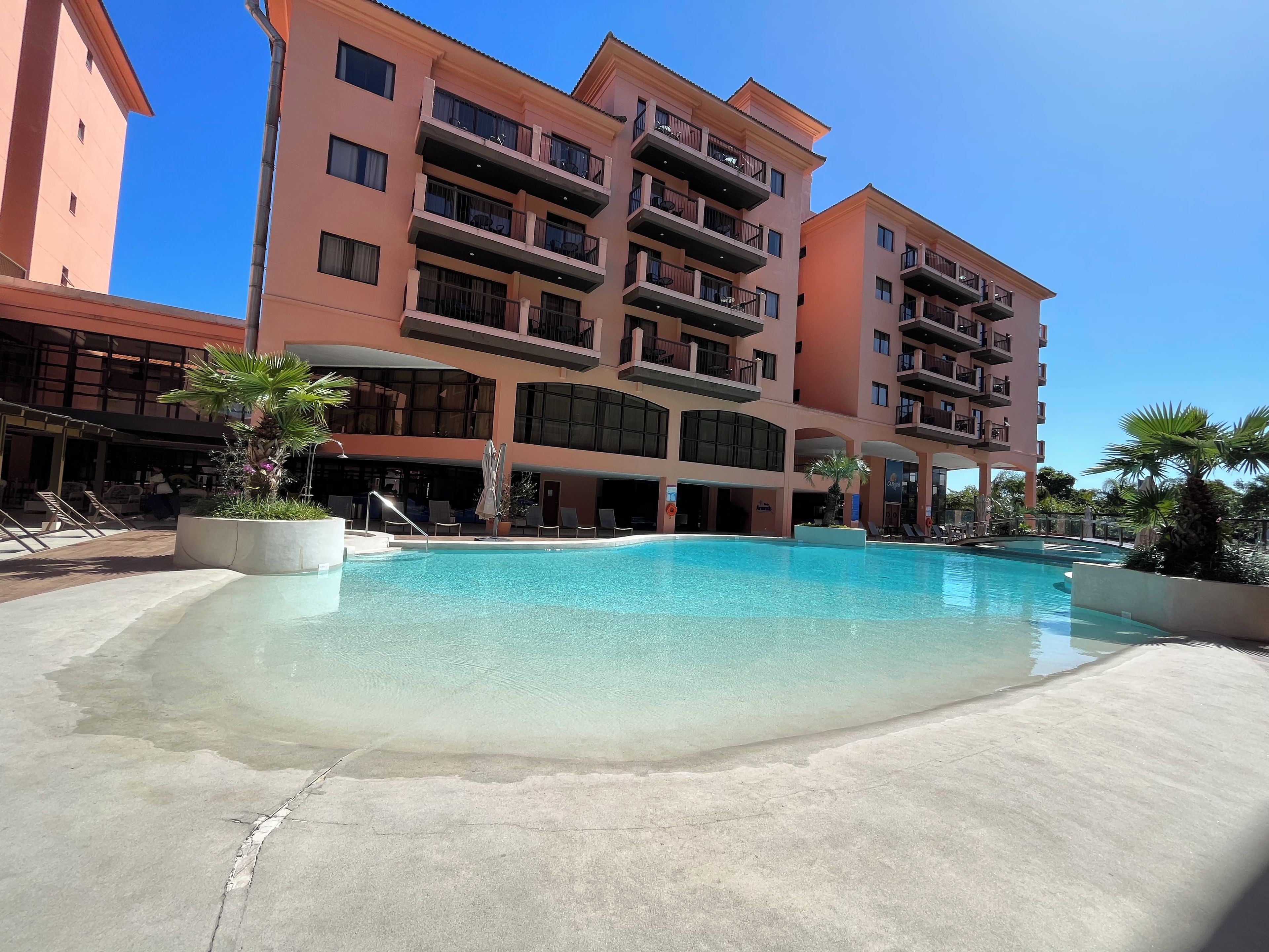 Et hotel med swimmingpool, flere balkoner og udendørs siddeområder.