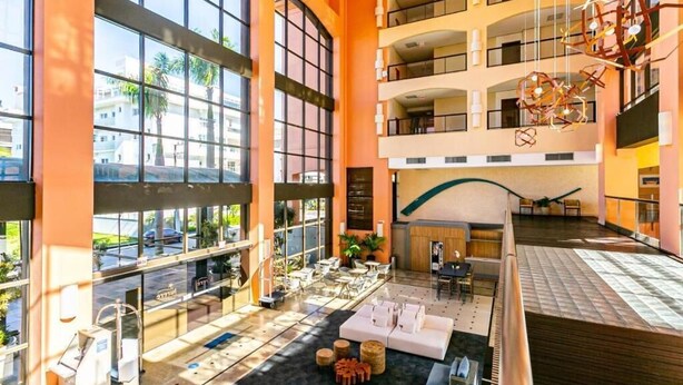 A spacious lobby with large windows, multiple floors, and modern furnishings. - Jurerê Beach Village (Florianópolis)