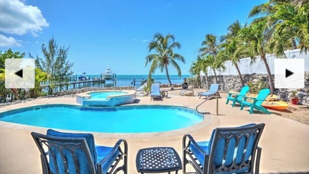 A pool area with lounge chairs and a view of the ocean. - 🌊 Private Oasis With Pool Spa Dock and Ocean right in your backyard 🌊 allow pets (Marathon)