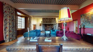 A spacious living room with a wooden coffee table, two sofas, and a fireplace. - A luxurious chateau in the Auvergne in a remarkable setting! (Cerzat)