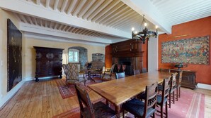 A traditional dining room with a large wooden table, ornate chairs, and a stone fireplace. - A luxurious chateau in the Auvergne in a remarkable setting! (Cerzat)
