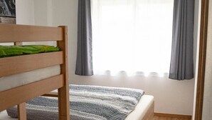 A bedroom with a bunk bed, a window with curtains, and a ceiling with a grid pattern. - Apartment at the Alpakahof (Kleinnondorf)