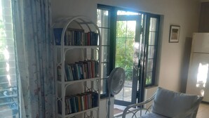 A living room with a white sofa, a bookshelf, a glass coffee table, and a white armchair. - Private Island w Causeway to Town, 2 Bedroom, 2 bathroom, Full kitchen, Sleeps 6 (George Town)