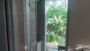 A room with a door leading to a garden area, a small table with a lamp, and a tiled floor. - Private Island w Causeway to Town, 2 Bedroom, 2 bathroom, Full kitchen, Sleeps 6 (George Town)