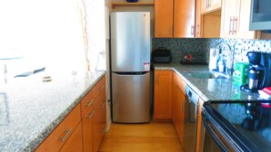 Una cocina con armarios de madera, un refrigerador de acero inoxidable, un microondas y una cafetera.