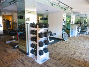 A gym with a mirrored wall, exercise equipment, and a rack of dumbbells.