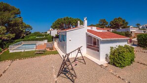 Un edificio blanco con techo rojo, una piscina pequeña y un columpio.