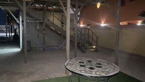 A covered outdoor area with a mosaic-tiled table, a hammock, and a staircase leading to an upper level. - loft morado (Puerto Peñasco)