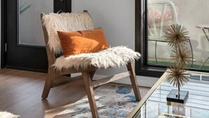 A modern living room with a chair, a decorative mirror, and a glass table.
